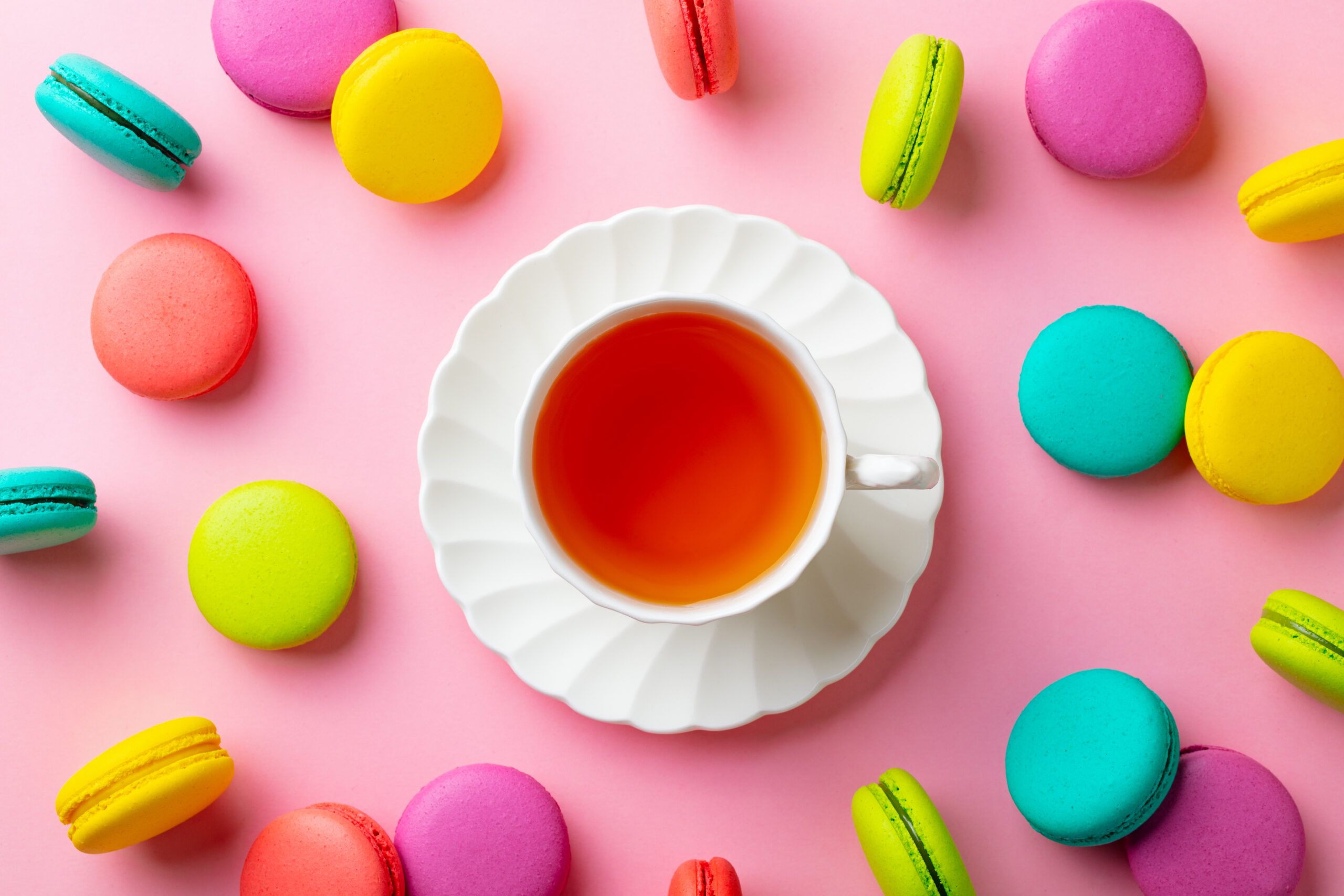 Cup of tea surrounded by colourful macarons representing Tea with Tracie Specialty Blends